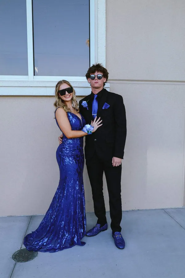 Young couple in prom attire — royal blue dress and black suit — posing together outdoors before the dance