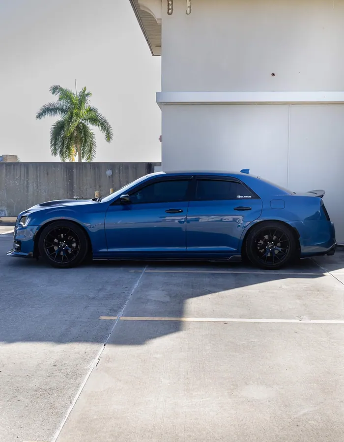 Side profile of a deep teal Chrysler 300 parked in a sunlit lot