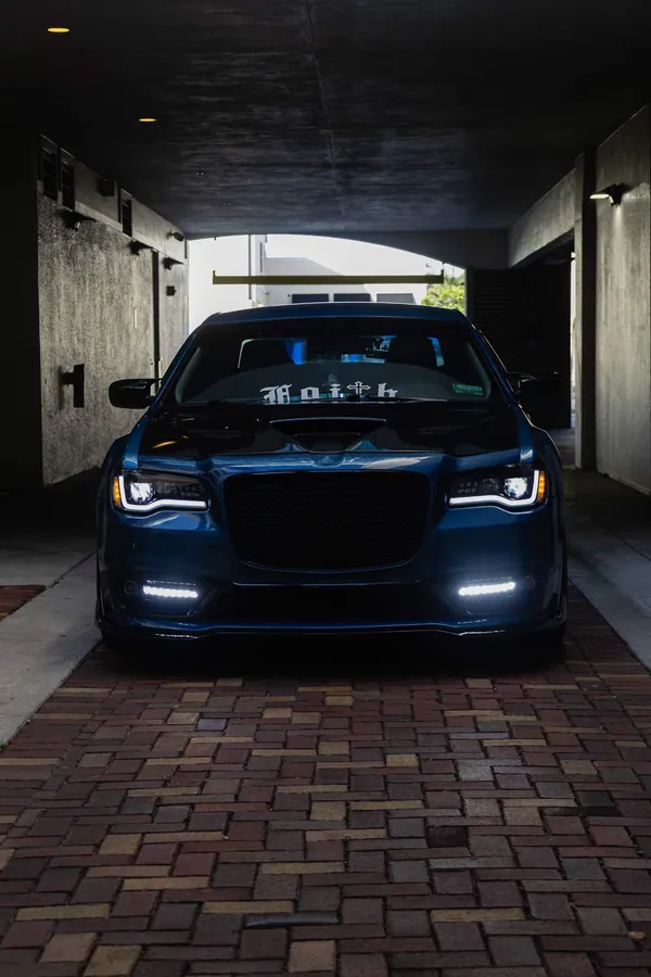 Front view of a deep teal Chrysler 300 parked inside a concrete parking structure