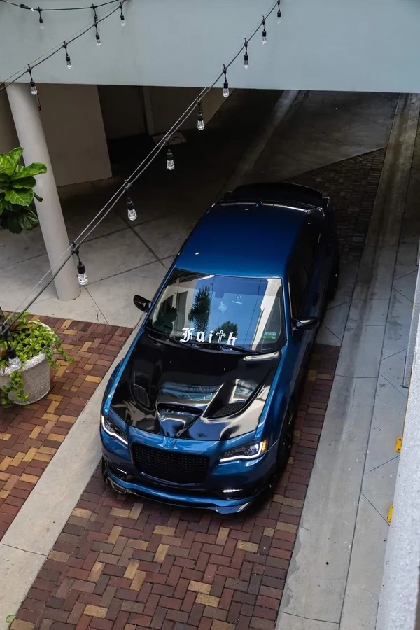 High angle of a deep teal Chrysler 300 in a courtyard strung with overhead lights